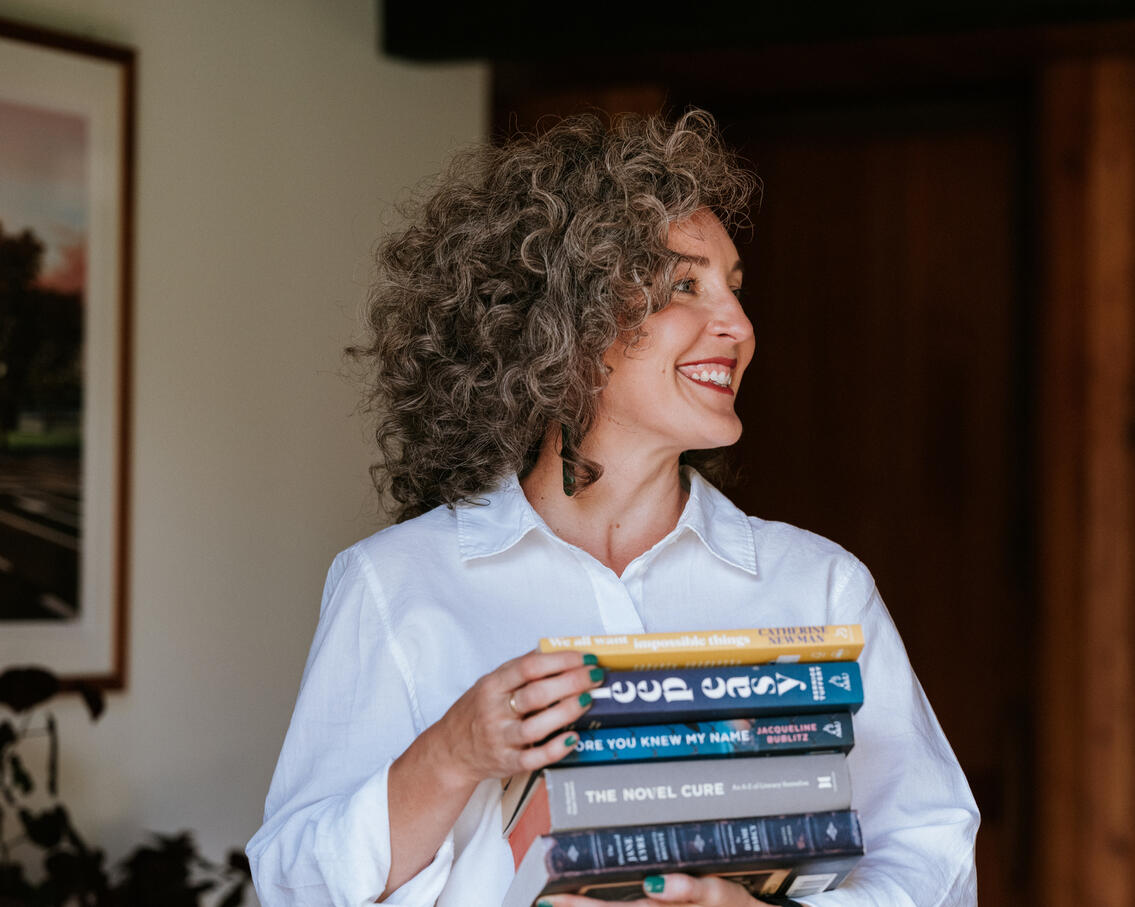 Kimberley Bartlett | Counselling & Sleep Therapy – Present State. Photo by Florence Charvin. Professional branding photo of Kimberley Bartlett, registered counsellor and sleep therapist, photographed holding books as a symbol of learning and curiosity